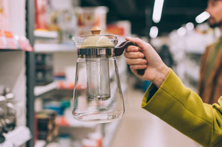 A girl holds a glass teapot in her hands in a supermarketの写真素材