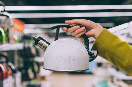 A girl holds a kettle in her hands in a supermarketの写真素材