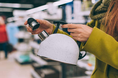 A girl holds a kettle in her hands in a supermarketの写真素材