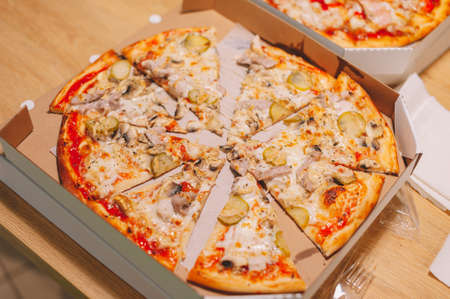 Pizza on the table, cut into piecesの写真素材