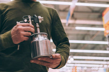 A man chooses a spray gun at a hardware storeの写真素材