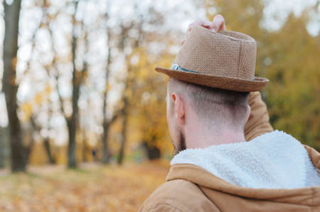A man in a hat on an autumn day against a background of beautiful leavesの写真素材