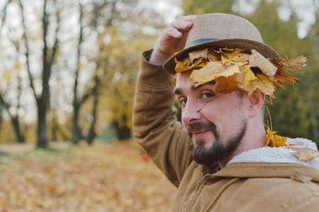 A man in a hat on an autumn day against a background of beautiful leavesの写真素材