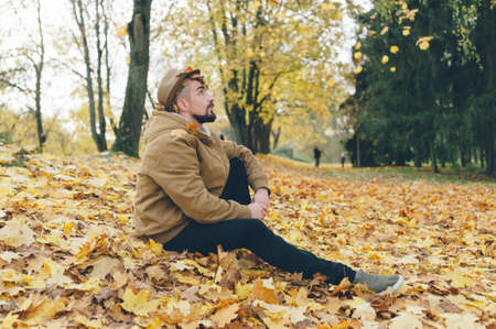 A man in a hat on an autumn day against a background of beautiful leavesの写真素材