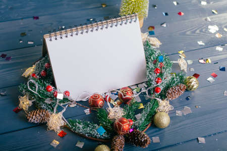 Festive composition for new year and christmas. Notepad on the background of a Christmas tree with decoration on a wooden tableの写真素材