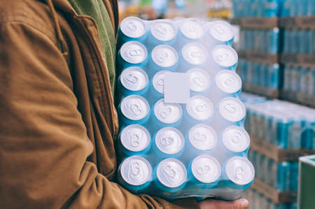 A shopper in a supermarket holds a package of beer in his handsの写真素材