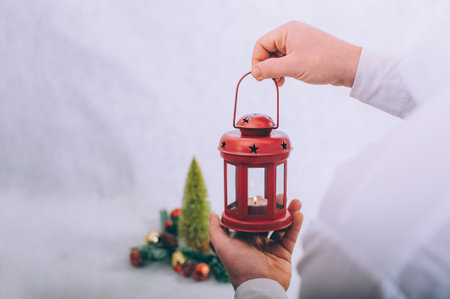 The guy holds a lamp with candles in his hands on the background of a Christmas compositionの写真素材