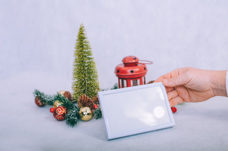 The guy is holding a mockup frame on the background of the Christmas compositionの写真素材