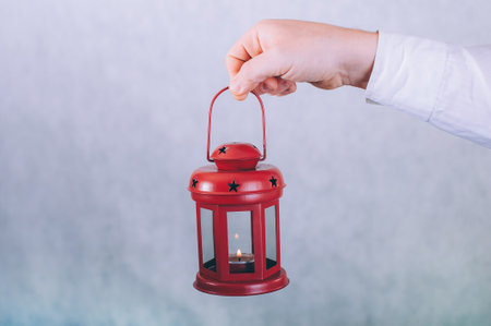 A man holds a lamp with a candle in his hands on a white backgroundの写真素材