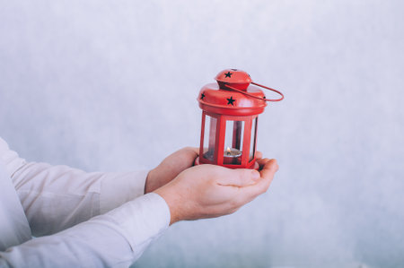 A man holds a lamp with a candle in his hands on a white backgroundの写真素材
