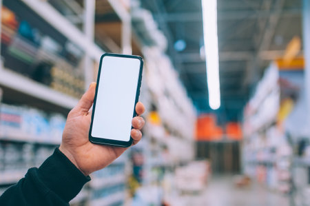 Mock-up technology. The guy holds a smartphone in his hands on the background supermarketの写真素材