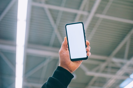 Mock-up technology. The guy holds a smartphone in his hands on the background supermarketの写真素材