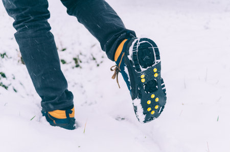 The man has ice shoes on his shoes. A people walks in the snow in winterの写真素材
