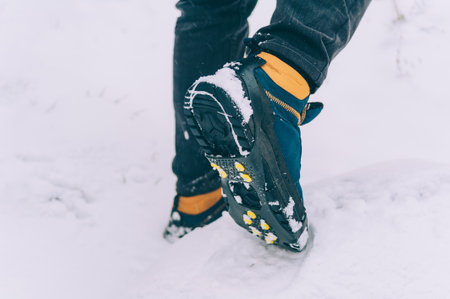 The man has ice shoes on his shoes. A people walks in the snow in winterの写真素材