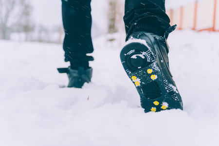 The man has ice shoes on his shoes. A people walks in the snow in winterの写真素材