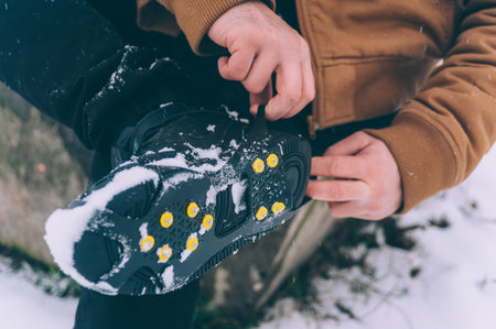 The man has ice shoes on his shoes. A people walks in the snow in winterの写真素材