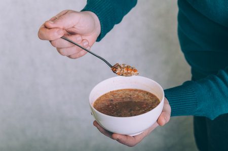 The man is eating broth soup from a bowlの写真素材