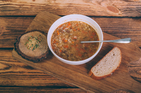 Soup broth in a bowl with bread on a wooden tableの写真素材