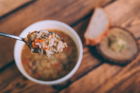 Soup broth in a bowl with bread on a wooden tableの写真素材