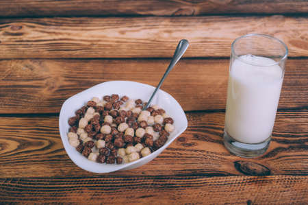 Cornflakes with a glass of milk on a wooden background