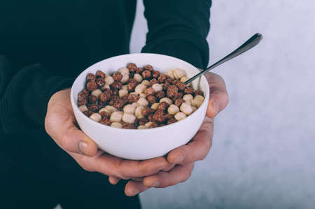 A man eating cornflakes with milk on a wooden background