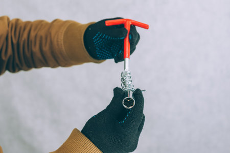 A man holds a construction screwdriver in his hands on a light backgroundの写真素材