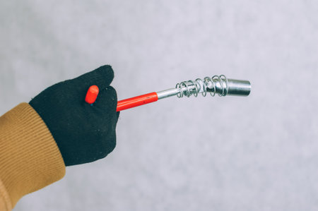 A man holds a construction screwdriver in his hands on a light backgroundの写真素材