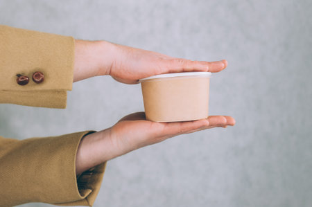 A man holds a mock-up of a paper cup for soup, coffee and tea on a light backgroundの写真素材