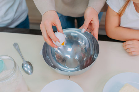 Mom teaches her daughters to cook dough in the kitchenの写真素材
