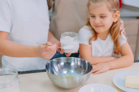Mom teaches her daughters to cook dough in the kitchenの写真素材