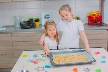 Two sisters are making homemade cookies in the kitchenの写真素材