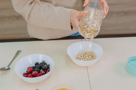 Mom prepares oatmeal with honey and fruit in the kitchen