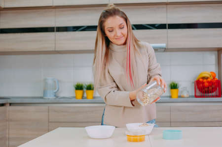 Mom prepares oatmeal with honey in the kitchenの写真素材
