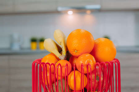 Fruit basket with oranges, tangerines and bananas in the kitchenの写真素材