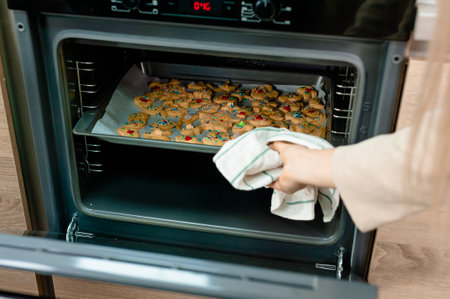 The girl opens the oven with cookiesの写真素材