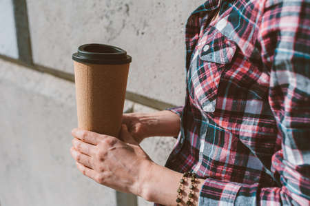 The girl holds a thermo mug with coffee in her handの写真素材