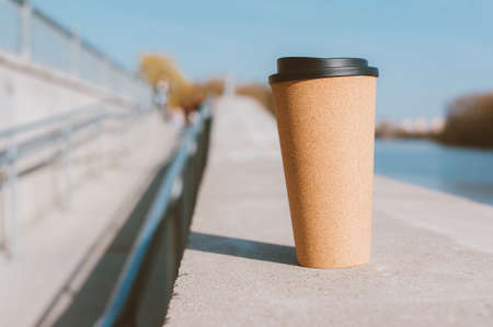 Thermo mug with coffee in the fresh air, on the background of the embankmentの写真素材