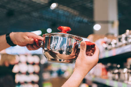 A man in a shop selects a new cooking potの写真素材