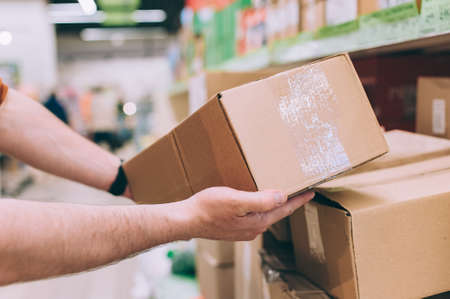 A man in a store holds a brown box in his handsの写真素材