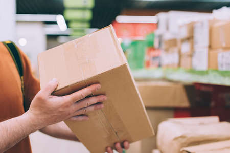A man in a store holds a brown box in his handsの写真素材