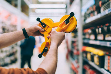 A man in a hardware store holds a tool for removing and transporting mirrors and glassの写真素材