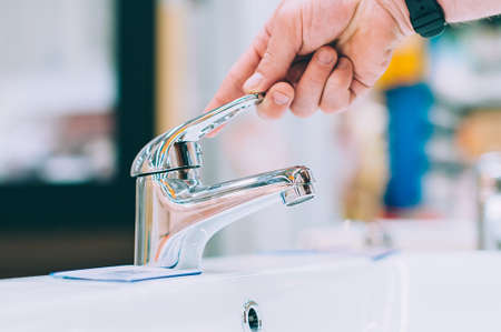 A man in a hardware store selects a faucet for the sink and washbasinの写真素材