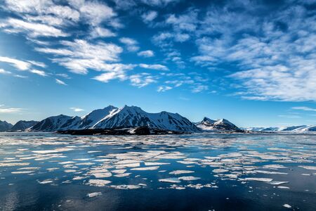 Svalbard peaks with clouds matching the ice in the waterの写真素材