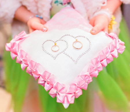 Girl holding wedding rings on a beautiful pillowの写真素材