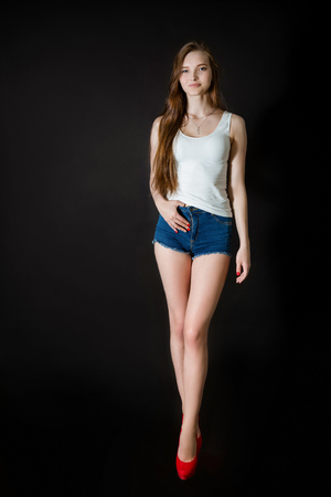 Attractive young woman smiling and posing in studio on black backgroundの写真素材
