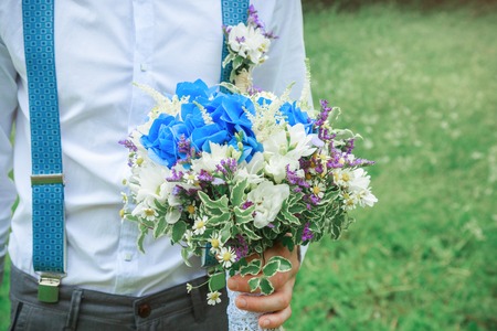 The groom is holding a wedding bouquet
