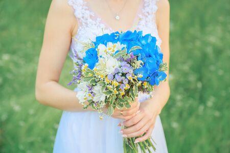 Bride is holding a wedding bouquet of natural flowersの写真素材