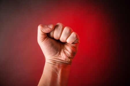 Male clenched fist on a red backgroundの写真素材