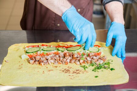 Cook prepares a shawarma. Ingredients on a big pita bread.の写真素材