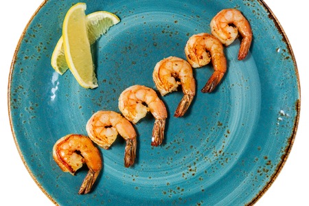 Fried shrimps with lemon on a blue plate. Closeup.